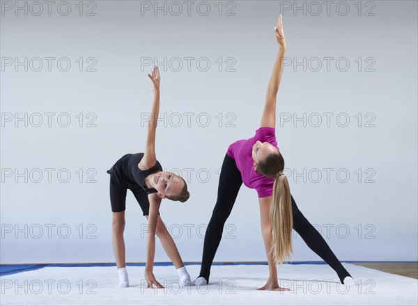 Training in the gym class. A little girl under the guidance of a trainer performs exercises. Gymnastics concept. Mixed media