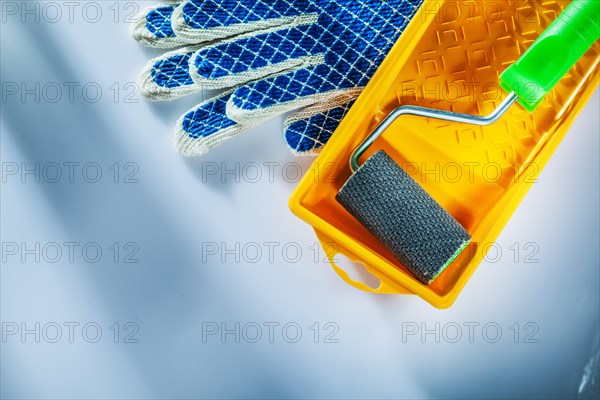 Pair of protective gloves paint tray roller on white background