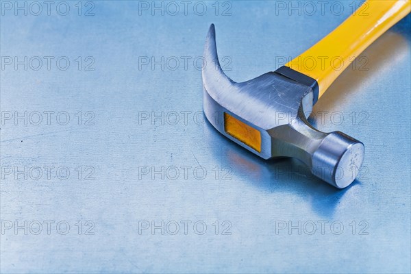 Copy space image of claw hammer with rubber grip on metallic background building concept