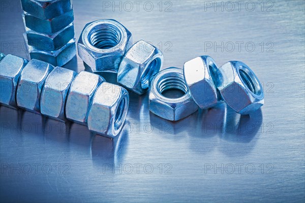 Horizontal version of stainless steel construction nuts on a metallic background Repair concept