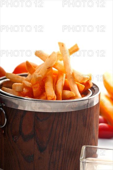 Fresh french fries on a wood bucket with white dip sauce and fresh vegetables on background