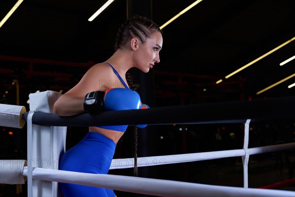 Beautiful and strong sportswoman posing in the corner of the ring. The concept of wrestling and boxing. Mixed media