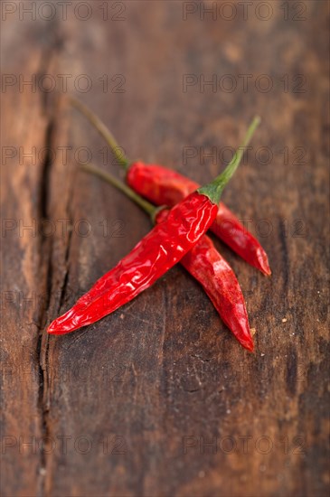 Dry red chili peppers over old wood table