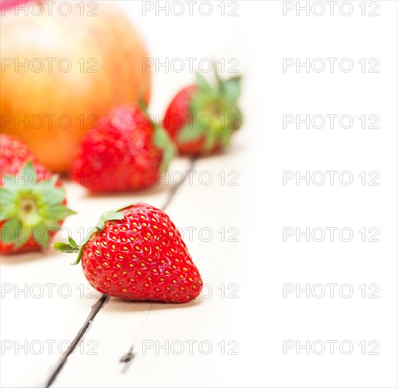 Fresh fruits apples pears and strawberry on a white wood table