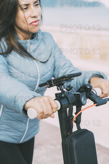 Beautiful woman riding her motorized scooter in the city along waterfront promenade