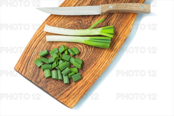 Green spring chopped scallion on wooden board and kitchen knife isolated white