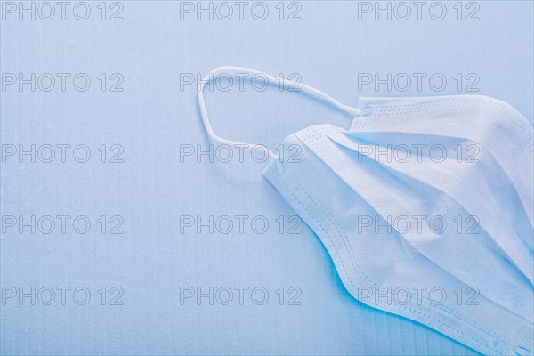 Disposable face mask on blue background with copy area
