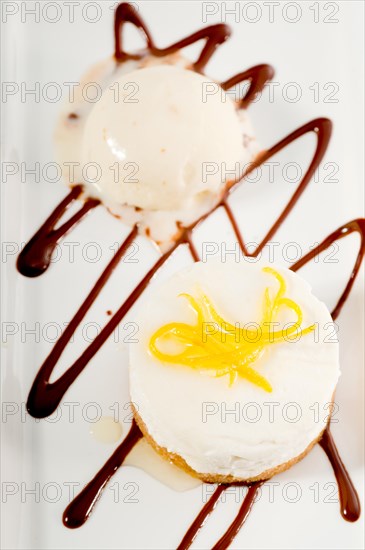 Very elegant lemon mousse dessert served whith lemon peel on top and vanilla ice cream on side