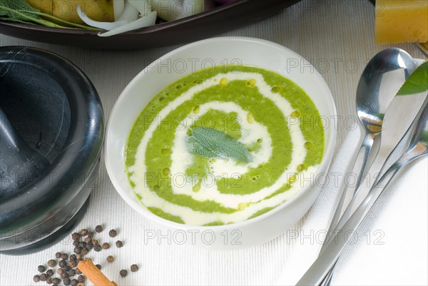 Fresh spinach soup on a white bowl with sage and cream on top