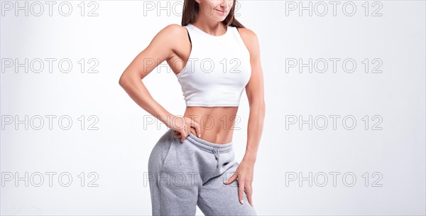 No name portrait. Young white fitness woman wearing sportswear standing over white wall background. Fitness concept. Mixed media