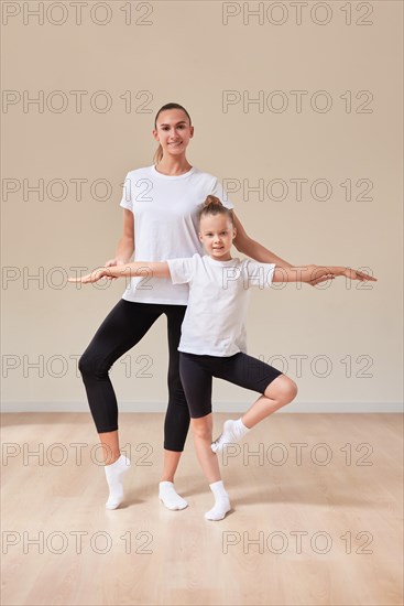 Beautiful woman teacher and a little girl perform dance movements in a bright studio. The concept of education