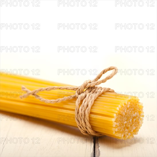 Italian pasta spaghetti tied with a rope on a rustic table