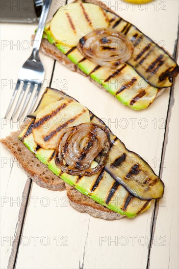 Grilled vegetables on rustic bread over wood table