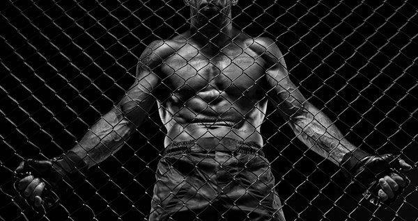 Black and white image of a man in a boxing cage. The concept of sports