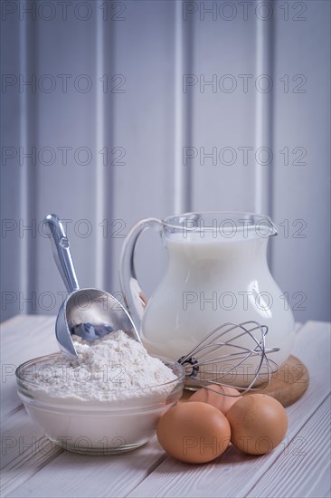 scoop flour into bowl egs corolla jug with milk on white lacquered old wooden board eating and drinking concept