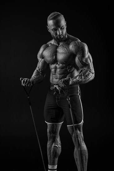 Silhouette of a strong bodybuilder. Confident young fitness athlete with a powerful body and perfect abs. Black and white photography. Dramatic light. Mixed media