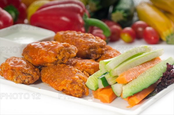 Classic buffalo chicken wings served with fresh pinzimonio and vegetables on background