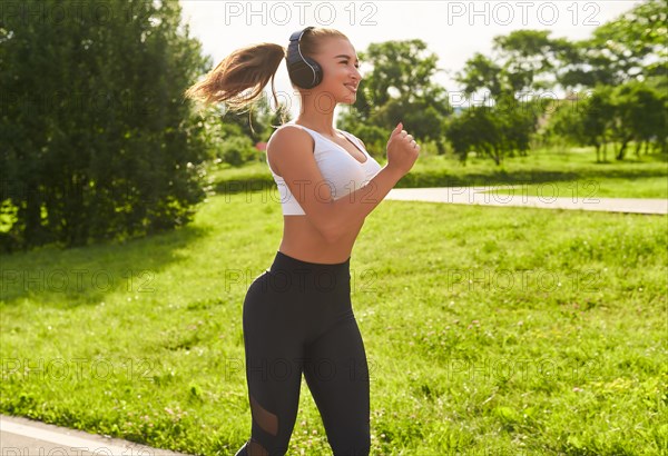 Fitness girl in sportswear runs through the evening sunny park. Healthy lifestyle. Mixed media