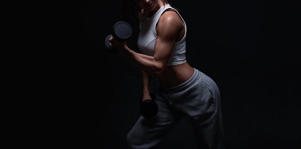 Athletic fitness woman posing in the studio on a dark background. Photo of an attractive woman in fashionable sportswear. Sports and healthy lifestyle. Mixed media