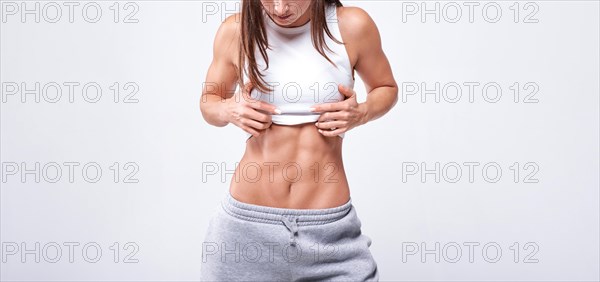 No name portrait. Young white fitness woman wearing sportswear standing over white wall background. Fitness concept. Mixed media