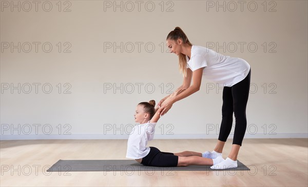 Beautiful female teacher helps a little girl stretch in a gymnastics class. The concept of education