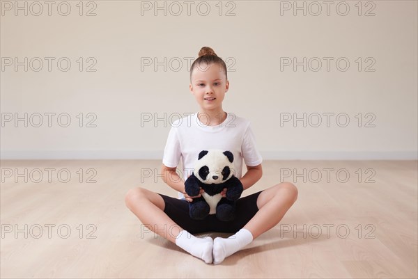 Cute girl child posing in the studio with a soft toy in a light studio. The concept of education