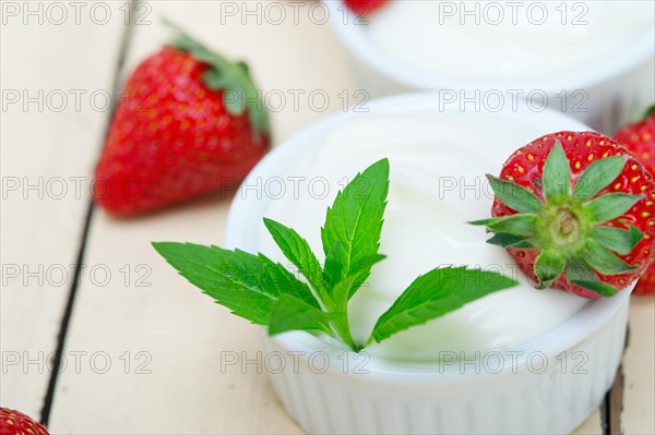 Organic Greek yogurt and strawberry over white rustic wood table