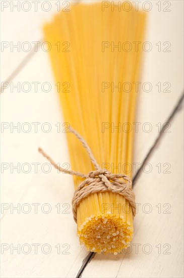 Italian pasta spaghetti tied with a rope on a rustic table