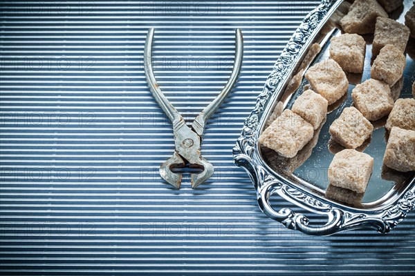 Brown sugar pliers tray on striped background