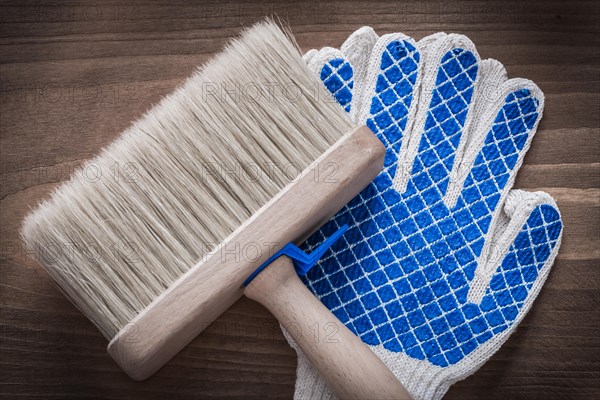 Paintbrush and protective gloves on vintage wooden background construction concept