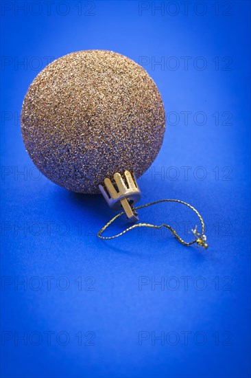 Single golden Christmas baubles on a blue background