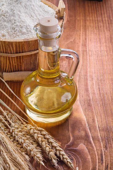 Oil bottle with ears of wheat and bucket of flour on old wooden boards