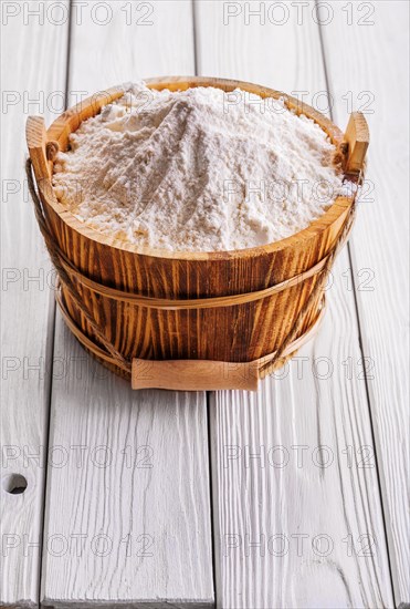 Flour in wooden buckets with handles on old white-painted wooden boards