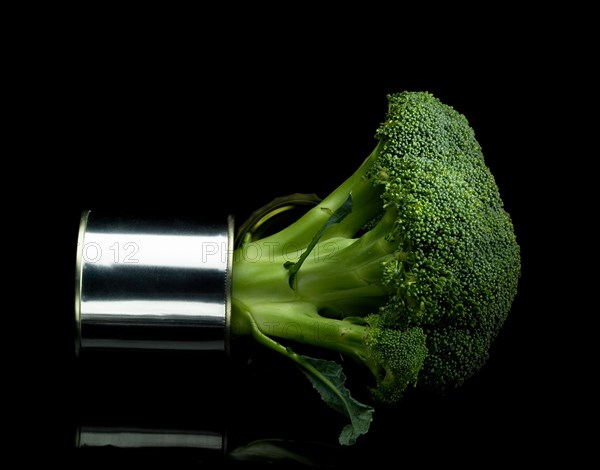 Fresh vivid green broccoli on a tin can over black background