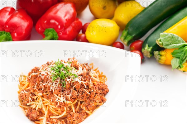 Italian classic spaghetti with bolognese sauce and fresh vegetables on background