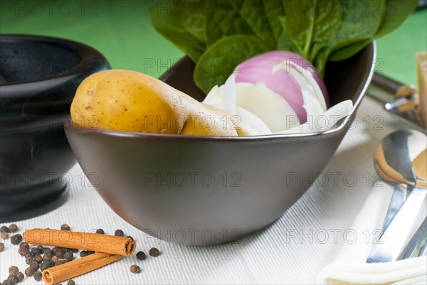 Bowl of fresh vegetable with spice and mortar beside