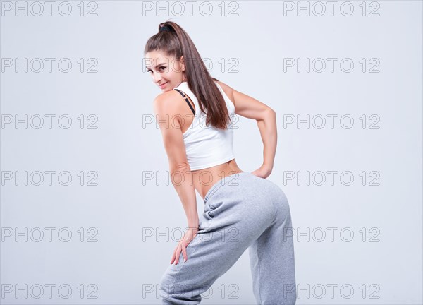 Young white fitness woman wearing sportswear standing over white wall background. Fitness concept. Mixed media