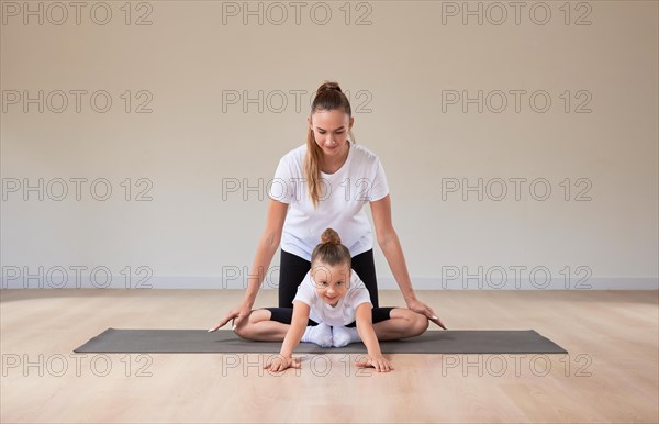 Beautiful female teacher helps a little girl stretch in a gymnastics class. The concept of education