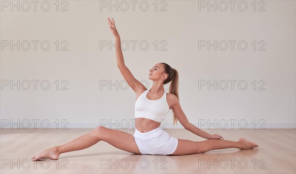 Flexible woman is training in a light studio. The concept of gymnastics