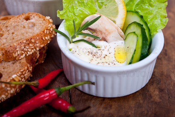 Fresh organic garlic cheese dip salad on a rustic table with bread