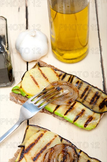 Grilled vegetables on rustic bread over wood table