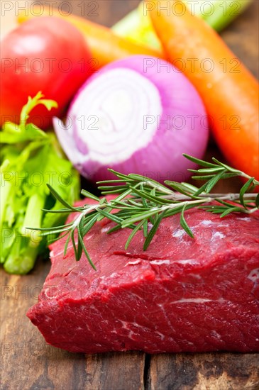 Fresh raw beef cut ready to cook with vegetables and herbs
