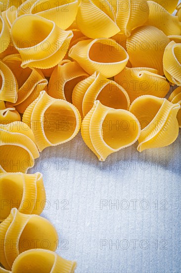 Heap of raw shell macaroni on blue background food and drink concept