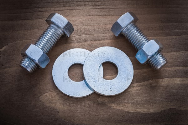 Bolt washers screwbolts and construction nuts on wooden background