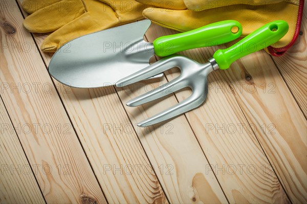 Hand spade and fork with gloves on wood. garden tools