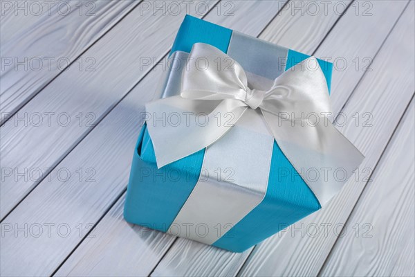 Blue gift box with white ribbon on a white wooden table