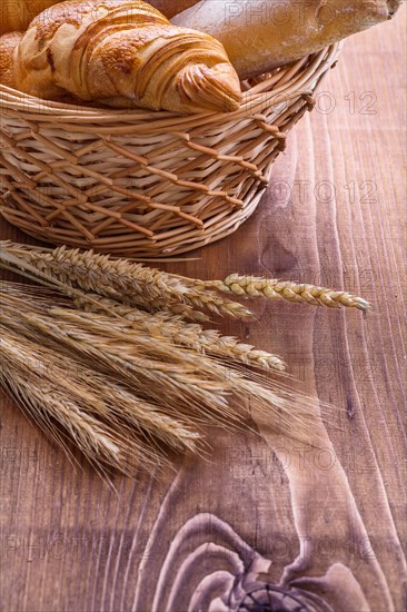 Croisants in a wicker basket and ears on an old wooden board