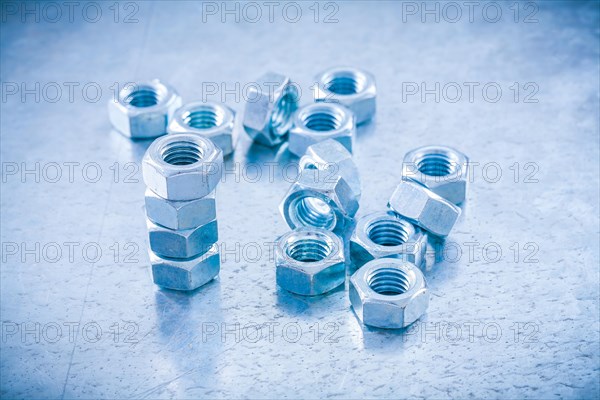 Metal threaded nuts on a metallic background Construction concept
