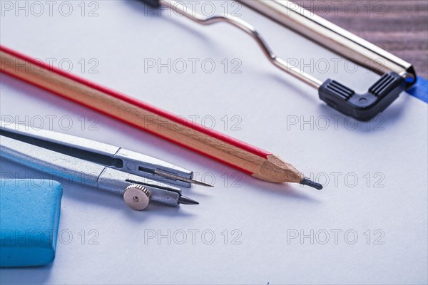 Eraser pencil compass and clipboard with paper on vintage wooden board Learning concept