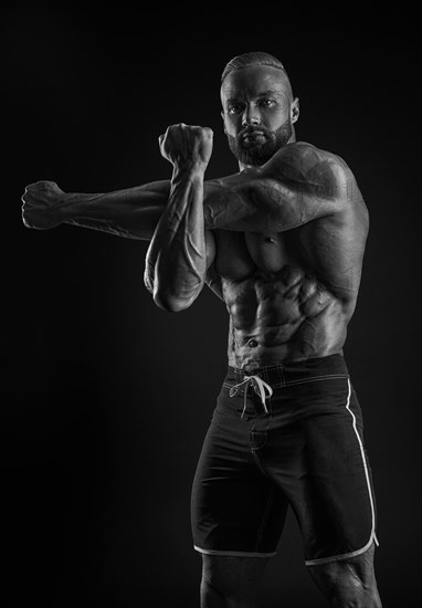 Silhouette of a strong bodybuilder. Confident young fitness athlete with a powerful body and perfect abs. Black and white photography. Dramatic light. Mixed media